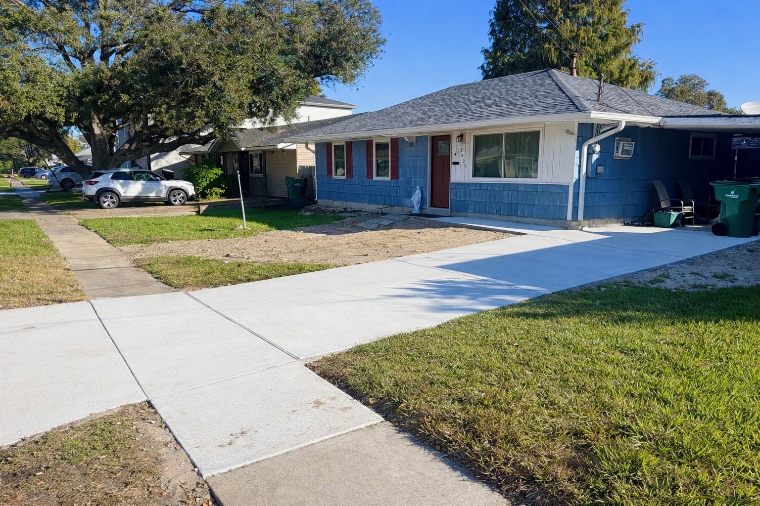 New concrete driveway in front of a blue home