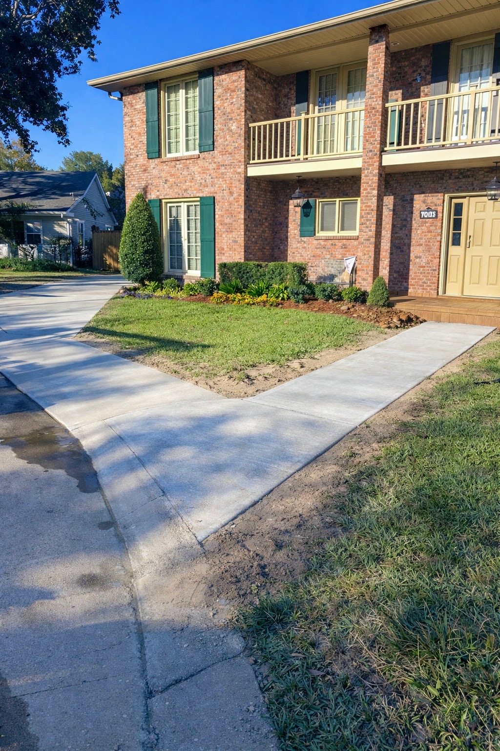 Fresh concrete walkway leading to a brick home